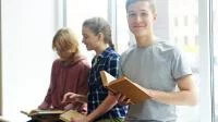 Drei Kinder sitzen auf einer Fensterbank und haben Bücher in der Hand 