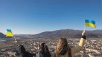 Frauen schwenken Ukraine-Flaggen mit Blick auf eine Stadt