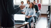 Eltern sitzen in einem Klassenzimmer und hören eine Präsentation
