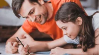 Ein Vater hilft seiner Tochter beim Erledigen der Hausaufgaben