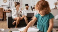Eltern sitzen hinter ihrem malenden Kind auf dem Sofa und planen den Tag