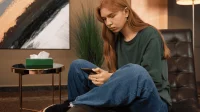 Eine Jugendliche sitzt mit ihrem Handy in einer psychotherapeutischen Praxis