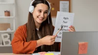 Ein Mädchen lernt Englisch-Vokabeln vor ihrem Laptop und trägt Kopfhörer