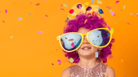 Ein Kind mit bunter Perücke und lustiger, großer Sonnenbrille wirft Konfetti in die Luft
