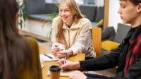 Junge Menschen sitzen bei einer Berufsberatung an einem Tisch mit einer Beraterin