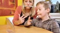 Mutter und Sohn machen logopädische Übungen zusammen