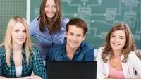 Gruppenfoto junger Erwachsener mit Laptop vor einer Tafel