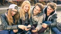 Vier Teenager betrachten Inhalte auf einem Smartphone