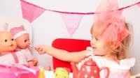Mädchen füttert eine Puppe umgeben von pinken Accessoires