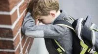 Foto eines Schülers, der den Kopf an eine Mauer lehnt
