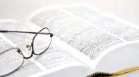 Foto einer Brille auf einem aufgeschlagenen Buch