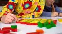 Kind spielt mit geometrischen Spielsteinen