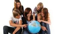 Gruppe von Schüler*innen umsteht einen Globus