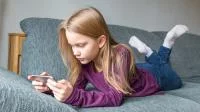 Ein Mädchen mit Smartphone auf dem Sofa