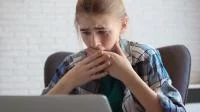 Ein schockiertes Mädchen vor dem Laptop
