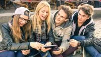 Gruppe Jugendlicher betrachtet gemeinsam Smartphone