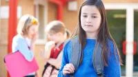 Ein Mädchen, abseits der Anderen traurig auf einem Spielplatz