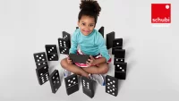 Mädchen sitzt in einem Kreis aus großen Dominosteinen