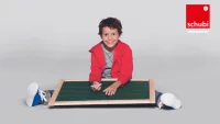 Kind sitz auf dem Boden und schreibt auf einer großen Tafel