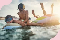 Kinder schwimmen mit Luftmatratzen und Schwimmringen im See