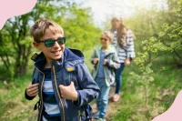 Kinder mit Sonnenbrillen spazieren durch den Wald in der Sonne