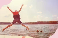 Kinder springen mit Schwimmwesten in einen See