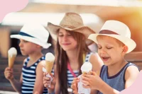 Drei Kinder mit Sonnenhüten essen Eis in der Sonne