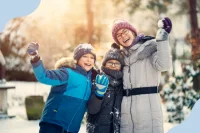 Drei Menschen halten lachend Schneebälle in den Händen