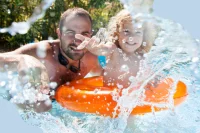 Ein Vater planscht mit seinem Sohn im Wasser in einem Freibad