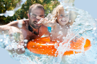 Ein Vater planscht mit seinem Sohn im Wasser in einem Freibad