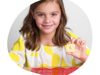 Abbildung von einem Mädchen, die das LÜK-Plättchen mit der Nummer 1 zeigt