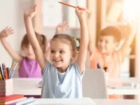 Lächelnde Kinder heben die Hände im Unterricht