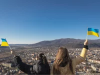 Frauen schwenken Ukraine-Flaggen mit Blick auf eine Stadt