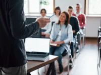 Eltern sitzen in einem Klassenzimmer und hören einem Präsentator zu