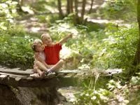 Zwei Kinder sitzen auf einer Brücke im Wald