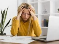 Frau sitzt vor ihrem Laptop und wirkt gestresst