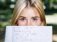 Frau hält ein Heft mit Matheaufgaben vor das Gesicht. Bild von Freepik