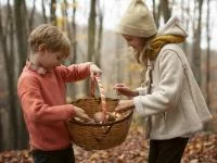 Zwei Kinder betrachten ihre gesammelten Pilze in einem Korb
