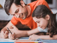 Ein Vater hilft seiner Tochter beim Erledigen der Hausaufgaben