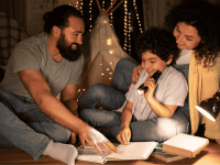 Eltern lesen mit ihrem Kind in gemütlicher Atmosphäre ein Buch