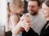 Ein Elternpaar hält ihre Tochter im Arm und dabei ihre Hand