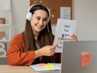 Ein Mädchen lernt Englisch-Vokabeln vor ihrem Laptop und trägt Kopfhörer