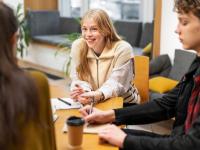 Junge Menschen sitzen bei einer Berufsberatung an einem Tisch mit einer Beraterin