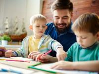 Vater malt zusammen mit seinen zwei Söhnen bunte Bilder