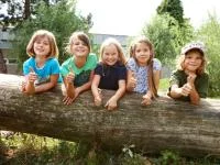 Gruppenfoto mit Kindern auf einem Baumstamm