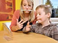 Mutter und Sohn machen logopädische Übungen zusammen