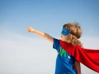 Kind im Superhelden-Kostüm und Pose