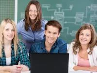 Gruppenfoto junger Erwachsener mit Laptop vor einer Tafel