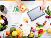 Tisch mit Obst, Gemüse, Tabellendiagrammen und Tblet