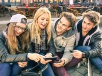 Vier Teenager betrachten Inhalte auf einem Smartphone